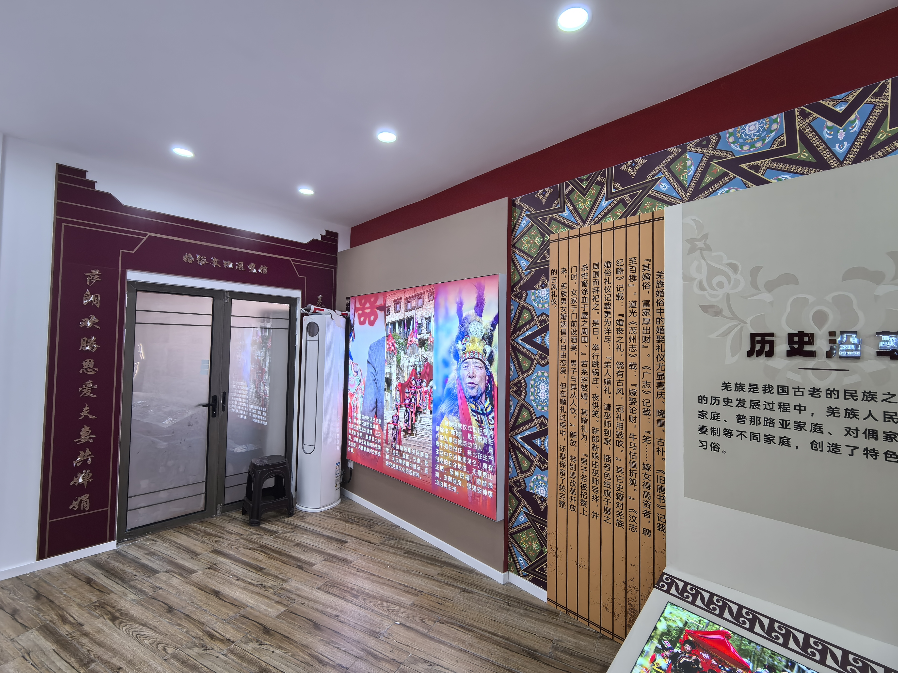 羌族婚俗发展史展览室入口，墙面介绍羌族婚俗历史沿革与文字说明，中央平面灯箱画面展示羌族传统婚礼场景