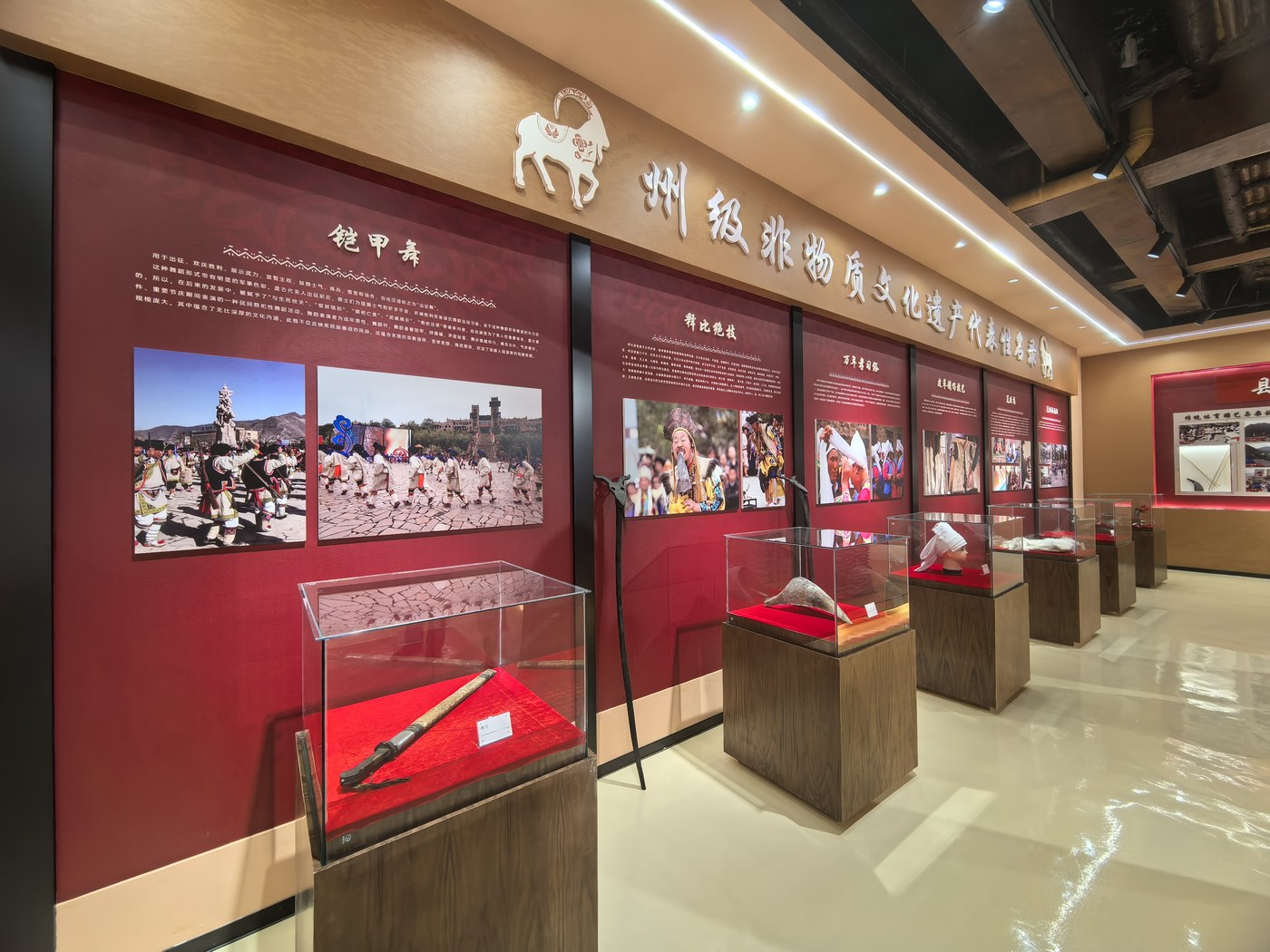 州级非物质文化遗产代表性项目名录墙：铠甲舞、拜北绝技等逐项标注，玻璃展柜陈列实物与展示台